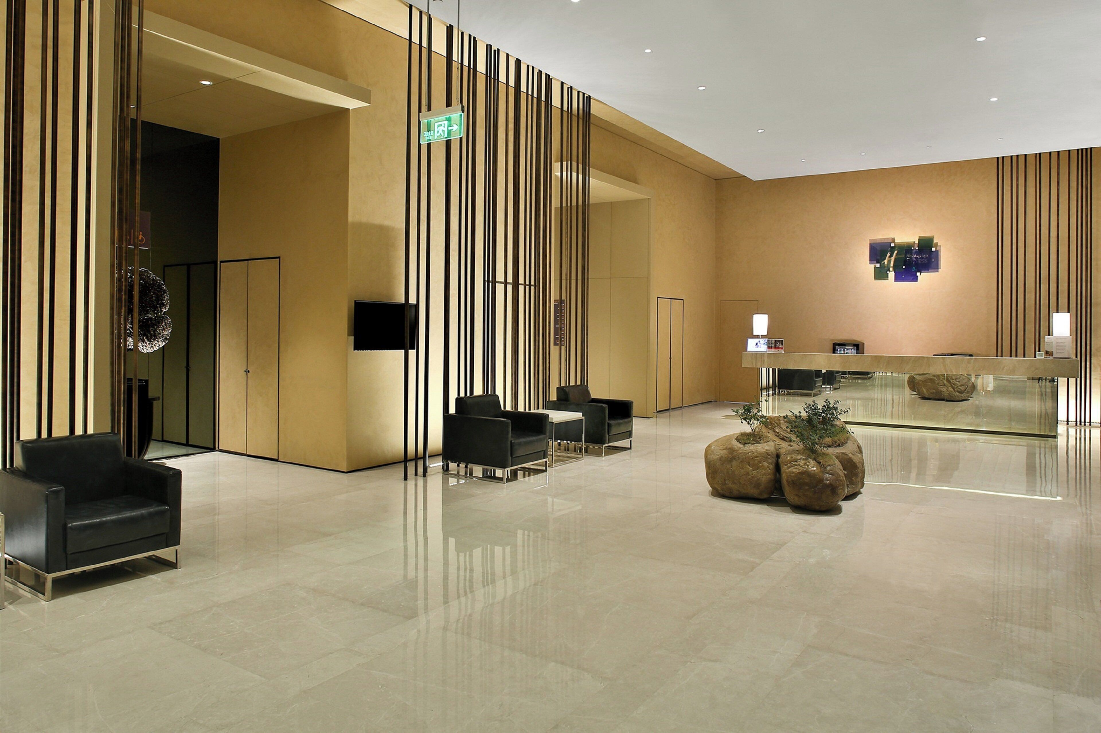 A modern lobby with a reception desk, seating area, and a decorative plant centerpiece.