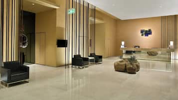 Un vestíbulo moderno con mostrador de recepción, zona de estar y un centro de mesa con planta decorativa.