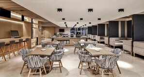 Un comedor moderno con sillas a rayas, una mesa larga y una zona de bar con una computadora portátil y teclado.