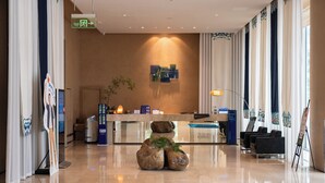 A modern hotel lobby with a reception desk, seating area, and a large window with curtains. - Holiday Inn Express Chengdu Wenjiang Hotspring by IHG (Chengdu)