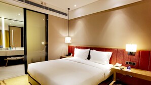 A hotel room with a large bed, a bedside table with a lamp, a mirror, and a bathroom visible through an open door. - Holiday Inn Express Chengdu Wenjiang Hotspring by IHG (Chengdu)