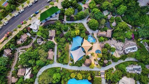 An aerial view of a resort with a swimming pool, multiple buildings, and a road with cars. - Holiday Inn Express Chengdu Wenjiang Hotspring by IHG (Chengdu)