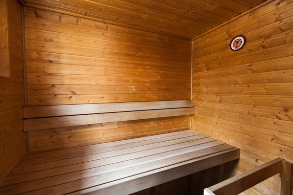 Una sauna de madera con bancos y puerta visible.