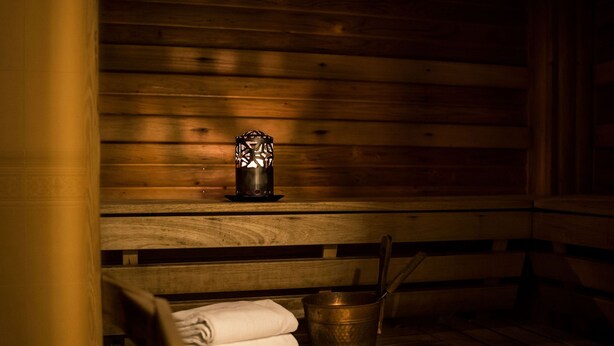 A wooden bench with a metal bucket and a candle.