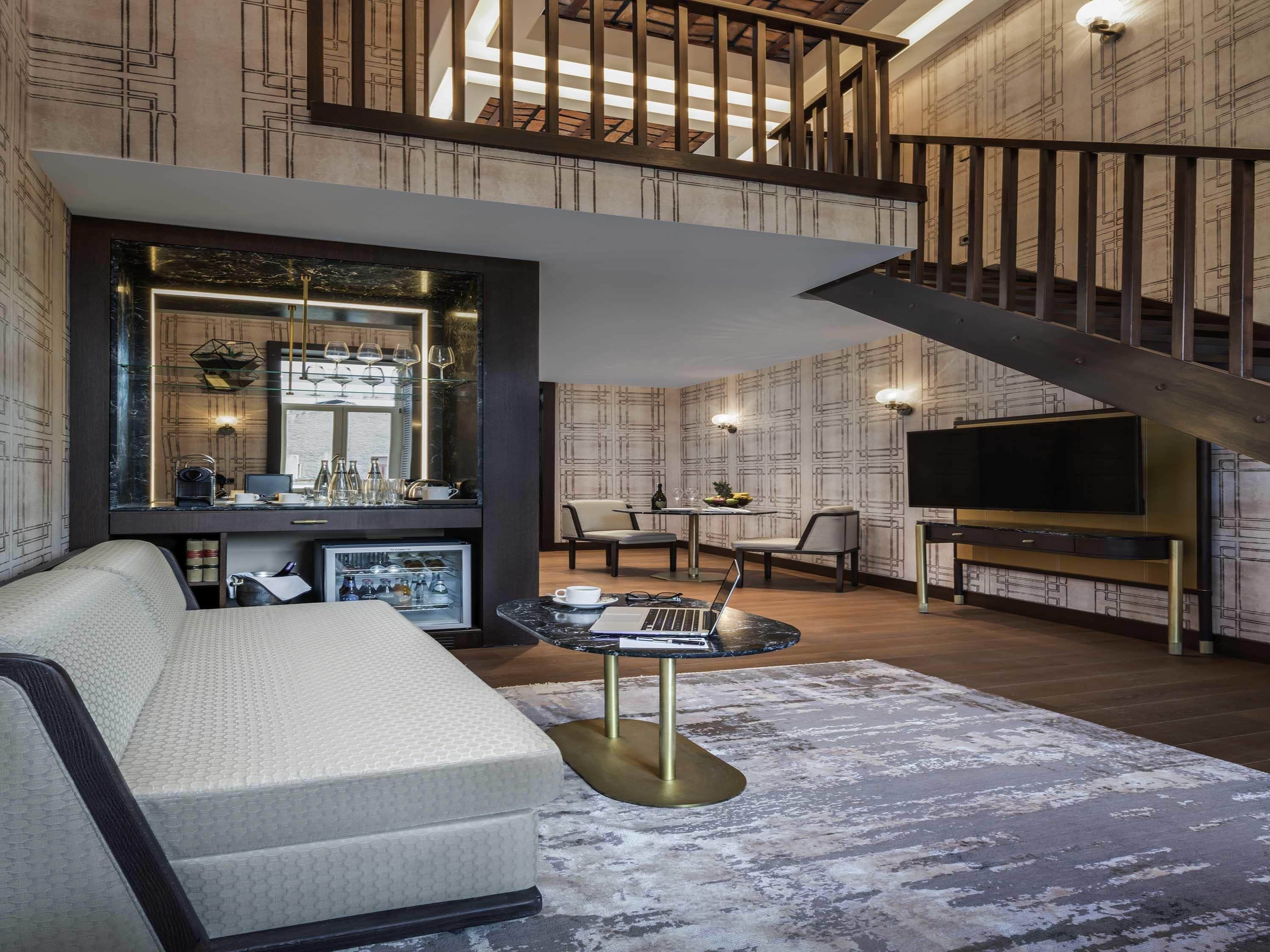 A modern living room with a sofa, a coffee table, a TV, and a staircase.