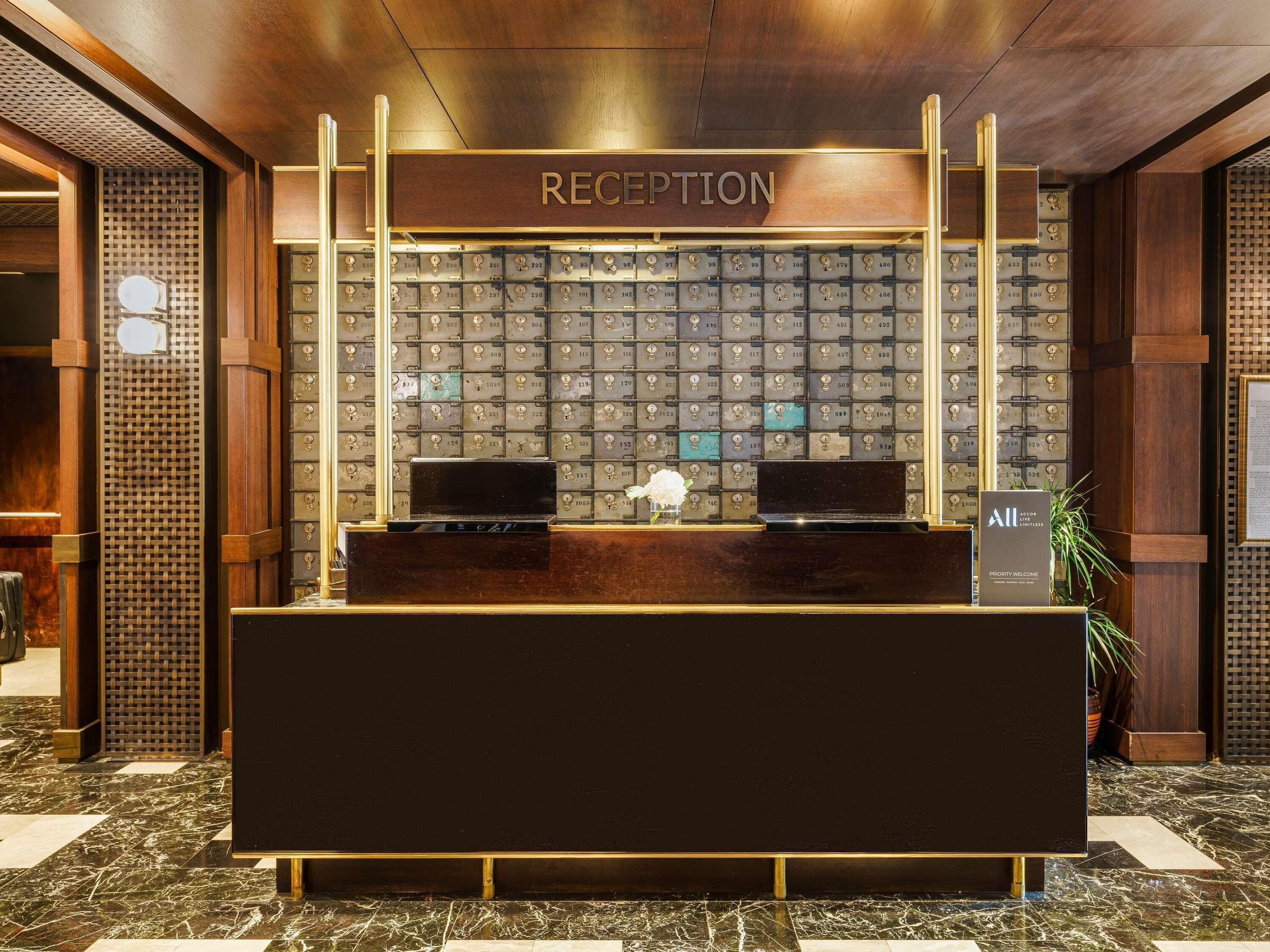 A reception desk with a wooden finish, a wall of numbered lockers, and a sign reading 'RECEPTION'.
