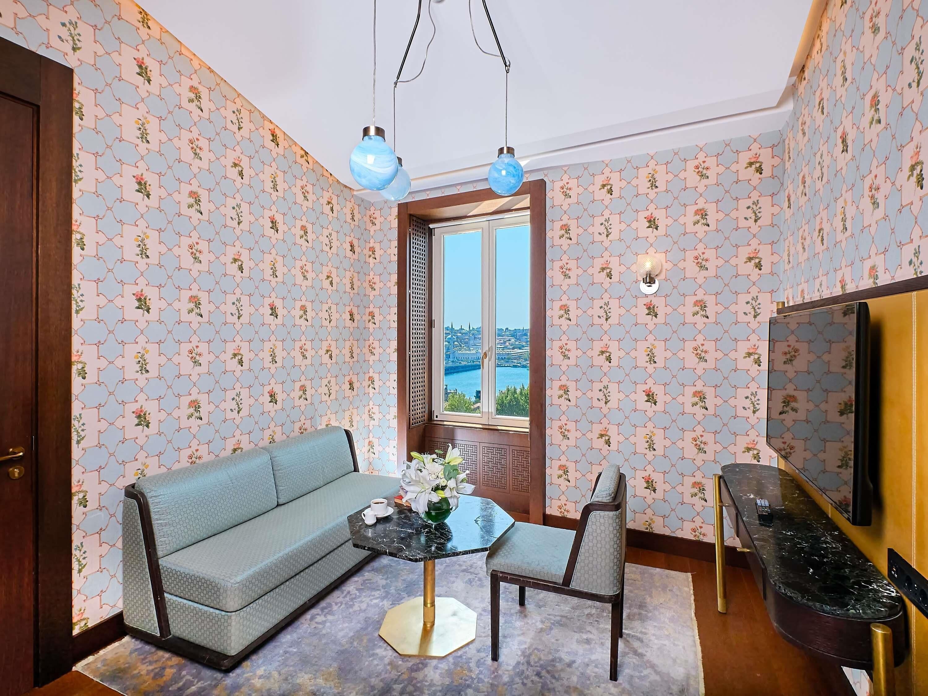 A room with a sofa, a dining table with chairs, a TV, and a window with a view.