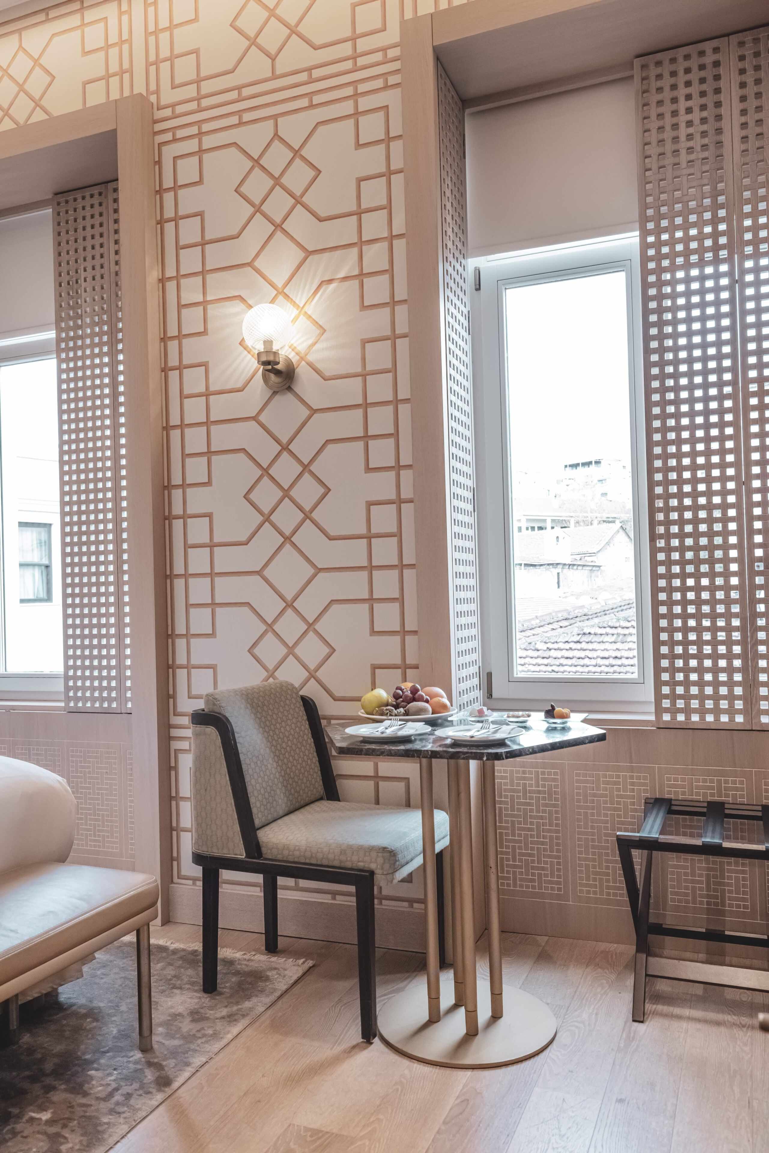 Een moderne kamer met een wand met geometrisch patroon, een ronde tafel met een stoel en een bank.
