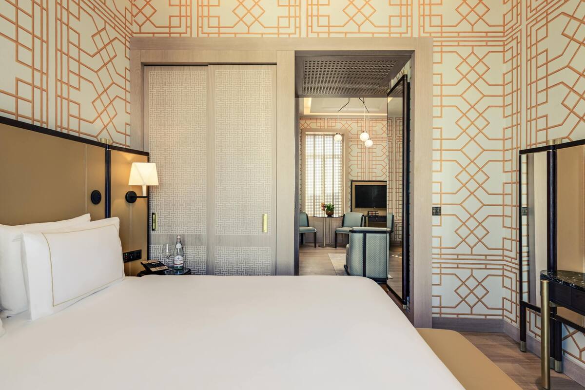 Ein Hotelzimmer mit einem großen Bett, einem Schreibtisch mit Stuhl, einem Fernseher und einem Spiegel.