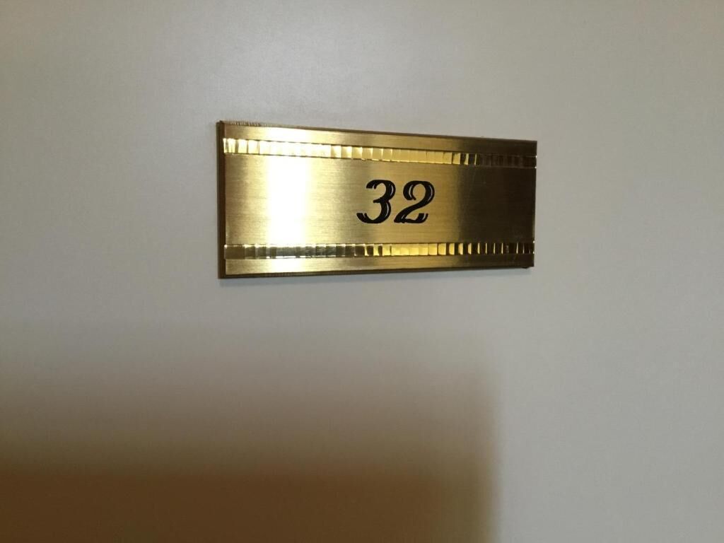 A metallic number plate with the number 32 on a wall.