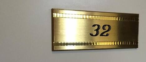 Une plaque métallique portant le numéro 32, fixée à un mur.