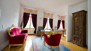 Una sala de estar con un sofá rojo, un sillón a juego, un mueble de madera y un televisor.