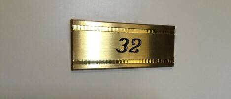 A brass room number plaque with the number 32.