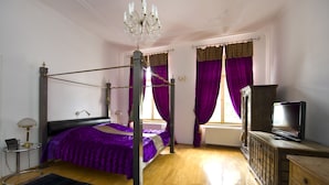 Un dormitorio con una cama con dosel, un televisor sobre un aparador de madera y un candelabro.