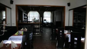 Ein Restaurant mit gedeckten Tischen, einer Bar und Blick durch große Fenster.