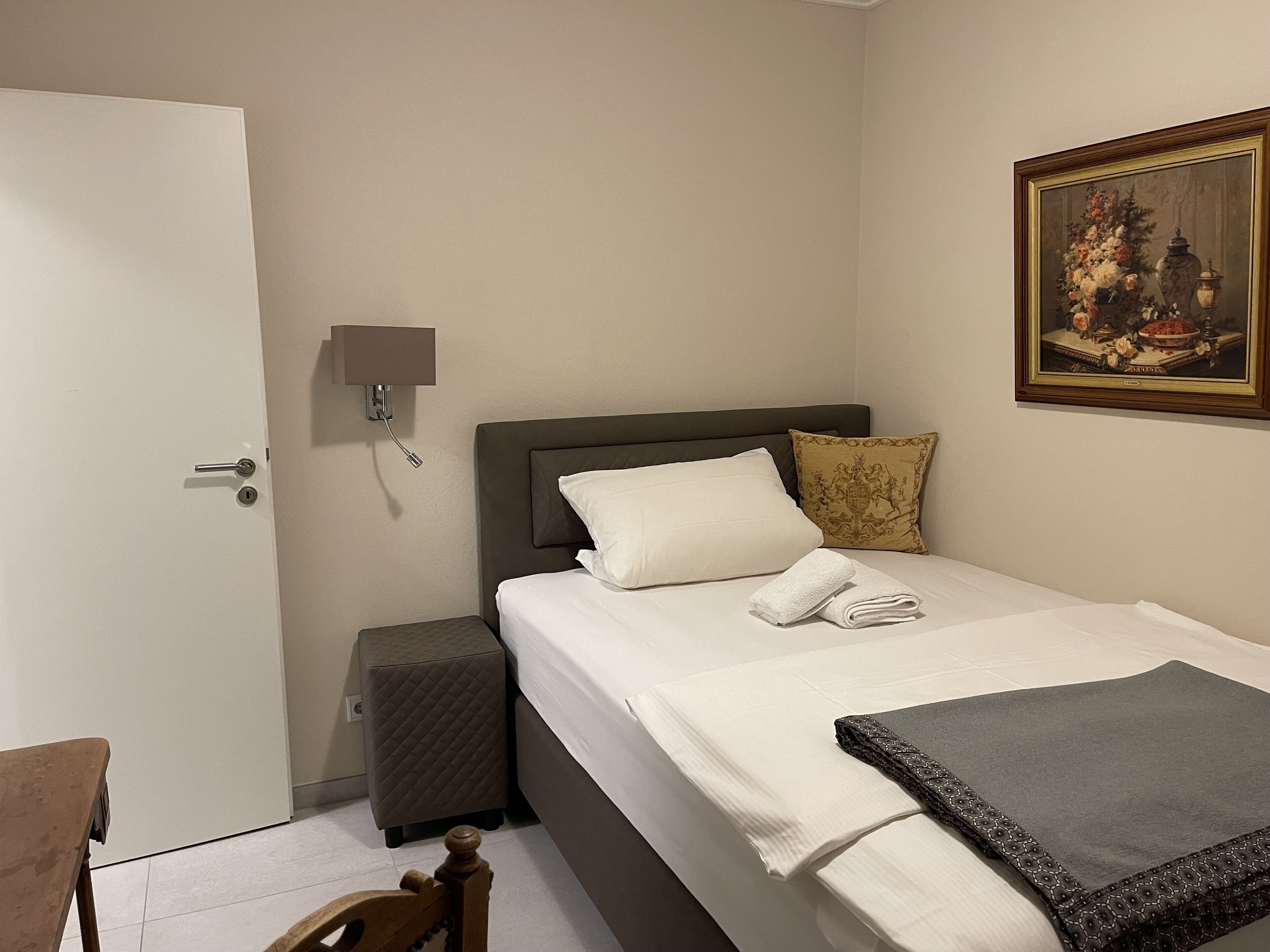 Une chambre d’hôtel avec un lit, une table de chevet, une commode, une lampe et un tableau au mur.