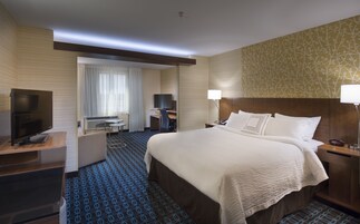 Una habitación de hotel con cama, escritorio, silla, televisor y lámpara.