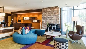 Un hall d'hotel modern amb una llar de pedra, una recepció i una zona de seients blava.