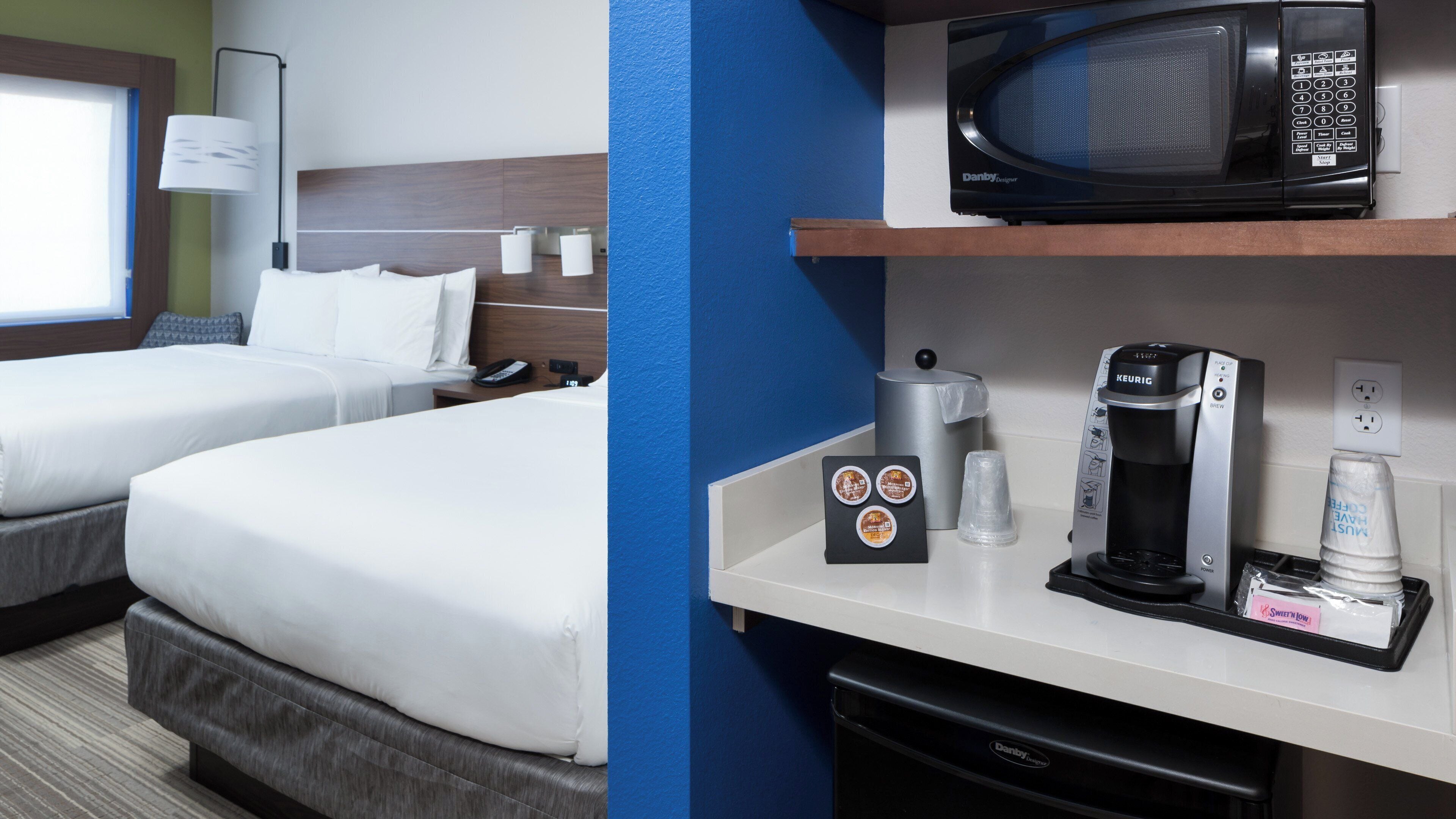 A hotel room with two beds, a microwave, a coffee maker, and a trash bin.