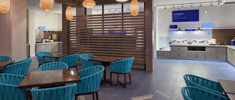 A modern restaurant interior with wooden slats, blue chairs, and hanging pendant lights.