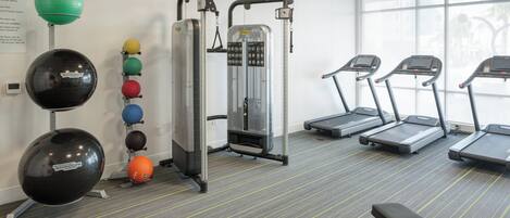 A fitness center with exercise equipment, treadmills, and a variety of balls.