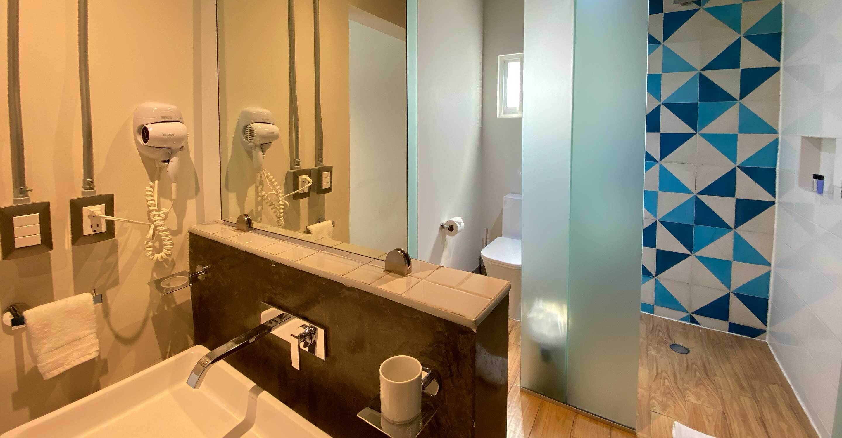 A modern bathroom with a glass-enclosed shower, a white bathtub, and a large mirror.