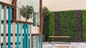 A staircase with teal railings, a bench, and a wall with green and purple foliage. - Hotel VIVE MX wtc CDMX, Trademark Collection by Wyndham (Mexico City)
