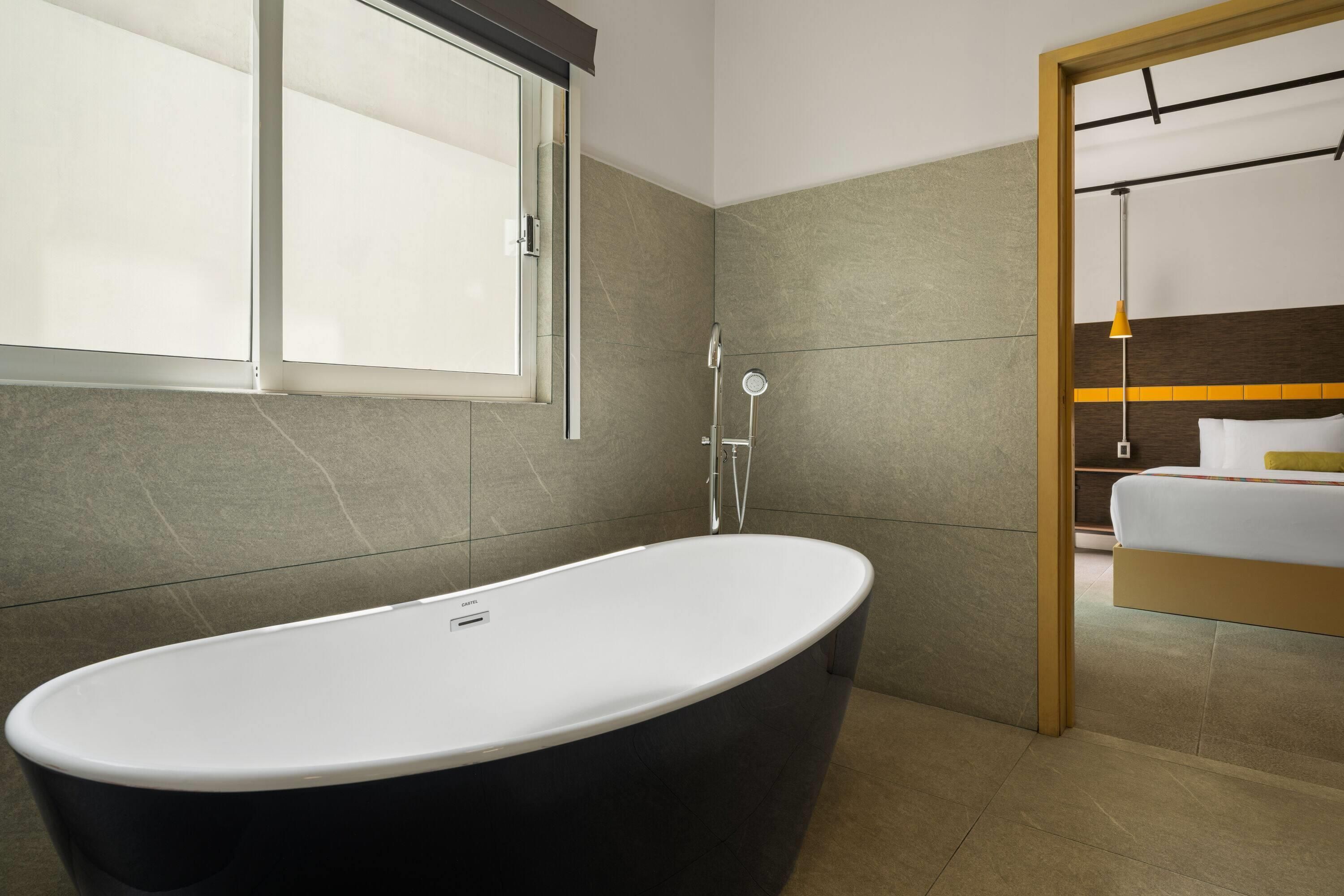 Un baño moderno con una bañera independiente, ducha y un ventanal grande.