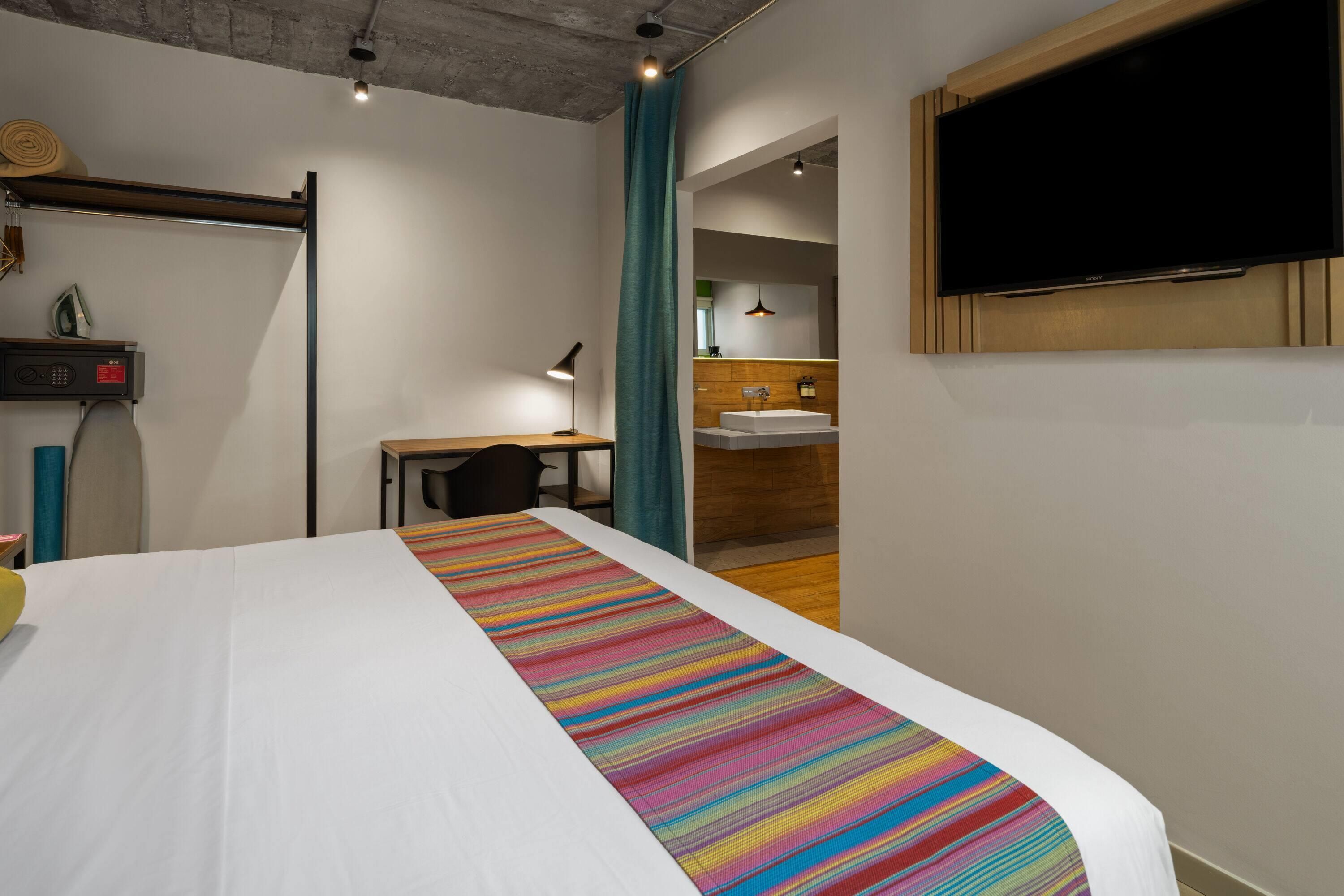 Een hotelkamer met een bed, een bureau, een badkamer en een televisie.