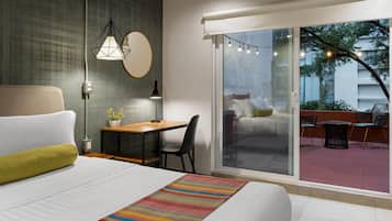 Una habitación de hotel moderna con cama, escritorio y vista al área exterior.