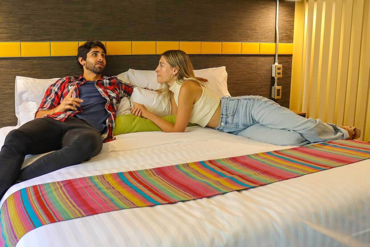 Habitació d'hotel amb un llit, una tauleta de nit i una presa elèctrica.
