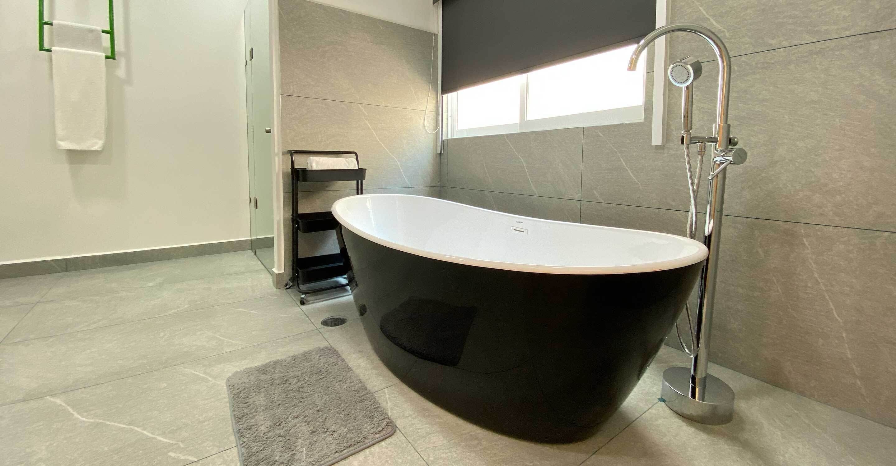 Ein modernes Badezimmer mit freistehender Badewanne, einem Handtuchhalter und einer Duschbrause.