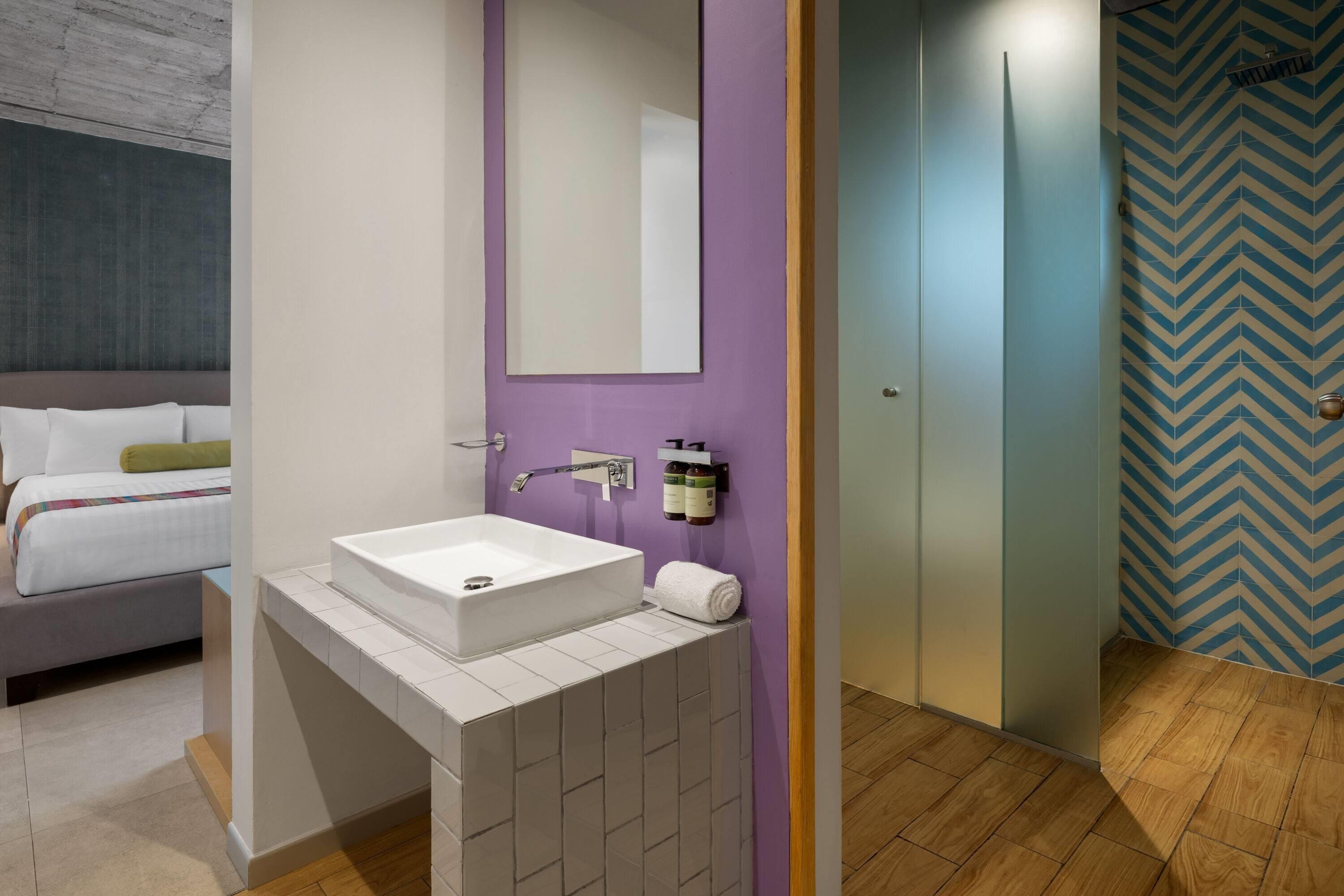 Ein modernes Badezimmer mit einem weißen Waschbecken, einem Spiegel und einem Handtuch.