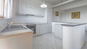Une cuisine moderne avec des meubles blancs, un plan de travail en granit et un four encastré.