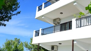 Un immeuble à plusieurs étages doté de balcons, d’un espace extérieur aménagé pour s’asseoir et offrant une vue sur un ciel dégagé.