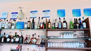 Des étagères remplies de bouteilles et de verres de différentes sortes d’alcool, ainsi que des récompenses obtenues au cours de différentes années.