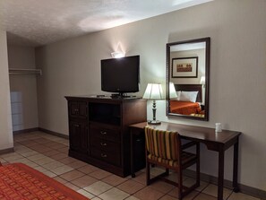 A hotel room with a dark wooden desk, a television, a lamp, a chair, and a mirror on the wall. - Reelfoot Lake Inn (Tiptonville)