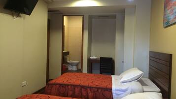 A hotel room with two beds, a TV mounted on the wall, a bathroom visible through an open door, and a painting on the wall.