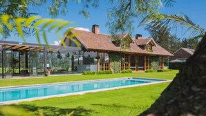 Ein modernes Haus mit Swimmingpool, überdachter Terrasse und üppigem Grün.
