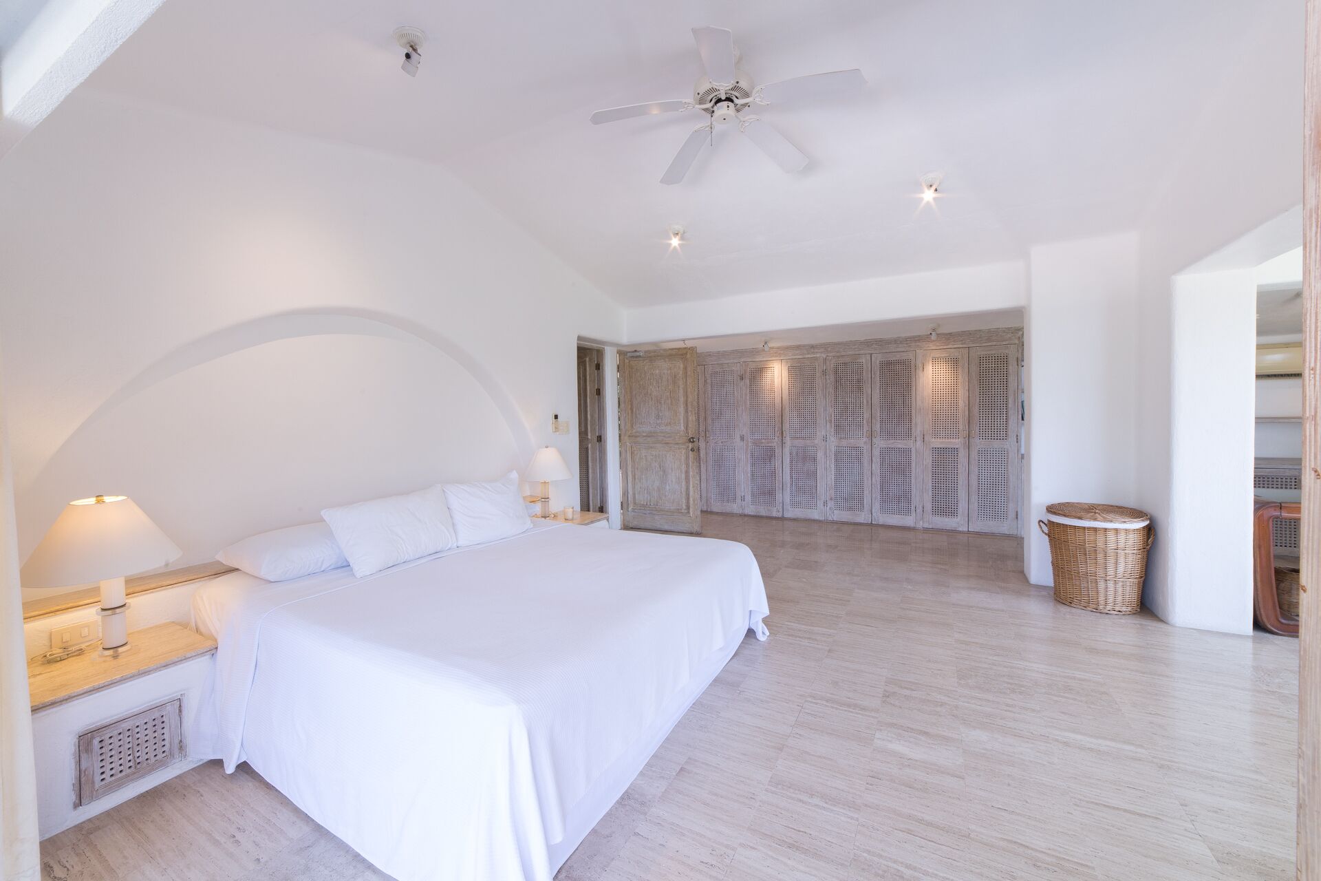 Un dormitorio amplio con una cama grande, un ventilador de techo y vistas a un balcón.