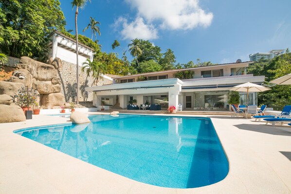 A modern pool area with a clear blue pool, lounge chairs, and a building with a covered patio. - Hermosa Villa Privada en Las Brisas, Acapulco (Acapulco)