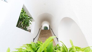A white-walled staircase with a wooden handrail, leading to an arched doorway at the top.