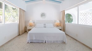 A hotel room with a large bed, two bedside tables with lamps, a ceiling fan, and large windows with curtains. - Exclusiva Villa Aldila frente al mar en Acapulco (Acapulco)