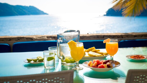 A table set with a pitcher, glasses, and a bowl of fruit by a seaside view. - Exclusiva Villa Aldila frente al mar en Acapulco (Acapulco)