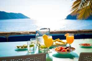 A table set with a pitcher, glasses, and a bowl of fruit by a seaside view. - Exclusiva Villa Aldila frente al mar en Acapulco (Acapulco)