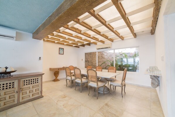 A dining area with a large table and chairs, a stone wall, and a view of the outdoors. - Exclusiva Villa Aldila frente al mar en Acapulco (Acapulco)