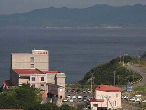 A coastal building with a parking lot and a road curving to the right. - Hotel Tappi (Sotogahama)