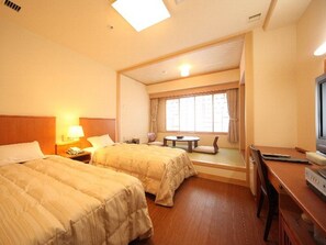 A hotel room with two beds, a desk, a television, and a window with curtains. - Hotel Tappi (Sotogahama)