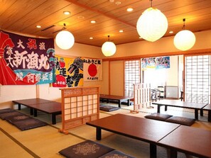 A traditional Japanese restaurant with tatami mat flooring, low tables, and hanging paper lanterns. - Hotel Tappi (Sotogahama)