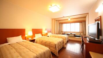 A hotel room with three beds, a television, a desk, and a window with curtains.